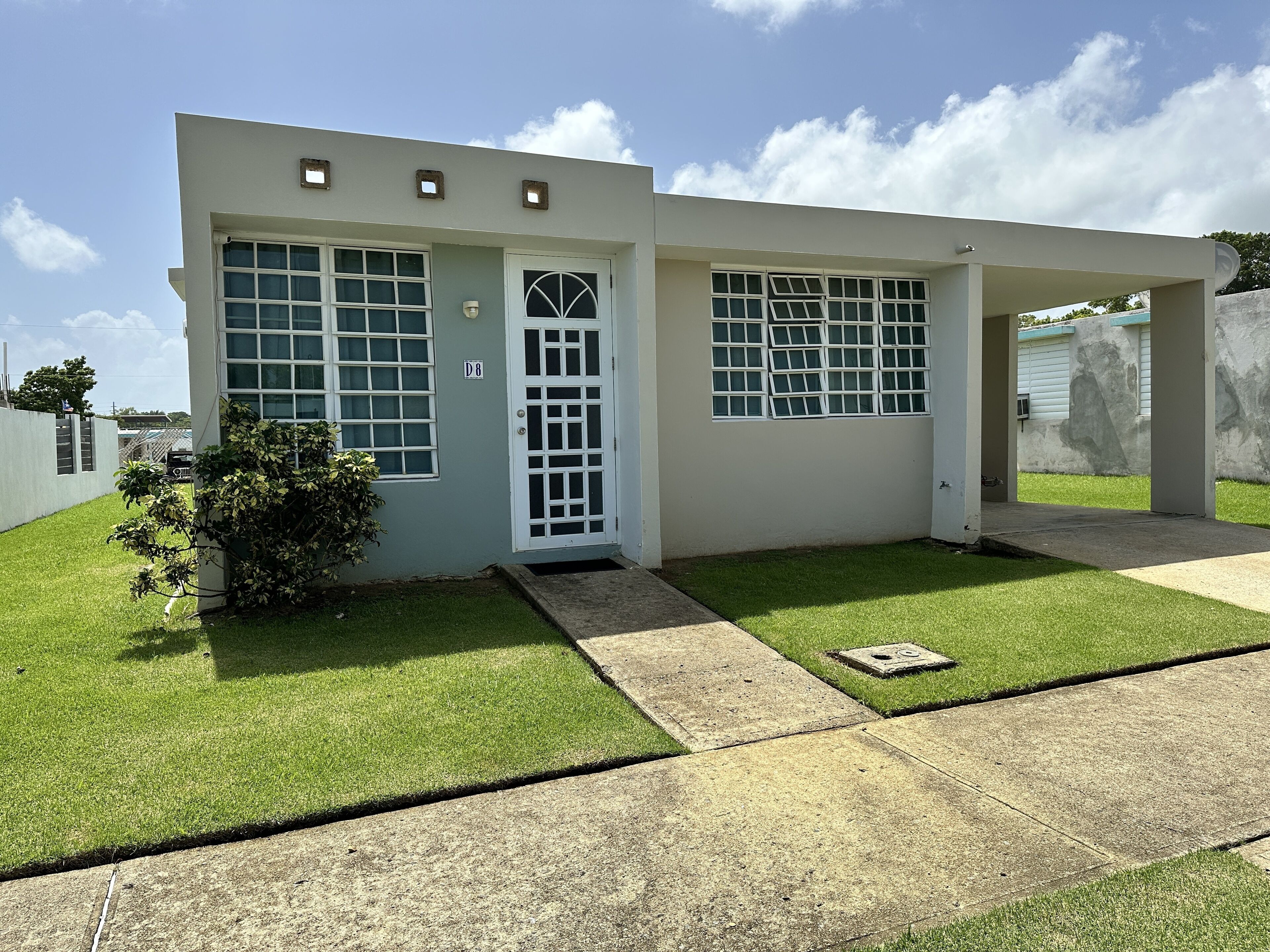 A modern two-story building with a white exterior and a small front yard.