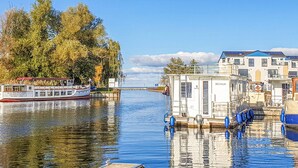 A river with a boat docked on the left and a small building with 'RECHLIN' on it on the right. - 2 bedroom stunning home in Rechlin (Rechlin)