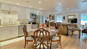 A spacious kitchen with modern appliances, a dining area with wooden chairs, and a living room with a television and decorative items.