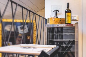 A room with a glass partition, a table with a book, a bottle of wine, and a box labeled "Paolo Scarpa". - [Old Town] - Corte D'Alba - Charming Suite (Alba)