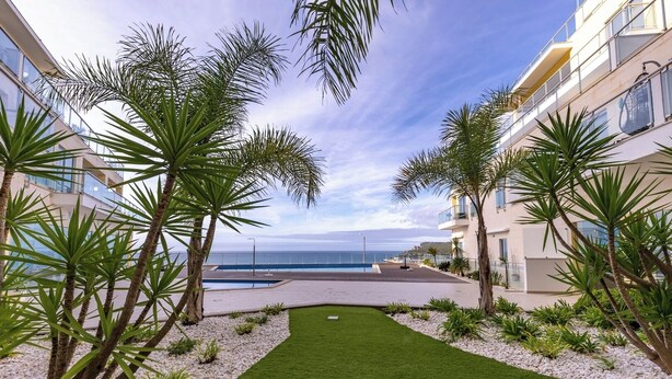 Ein Innenhof mit Pool, Palmen und Blick auf das Meer.