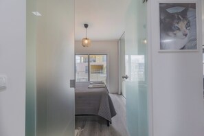 Ein modernes Schlafzimmer mit Bett, einer Hängelampe und Blick auf den Balkon.