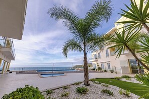 Ein Innenhof mit Pool, Palmen und Blick aufs Meer.