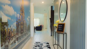 A hotel hallway with a large Disney castle mural, a welcome sign, and a mirror on the wall.