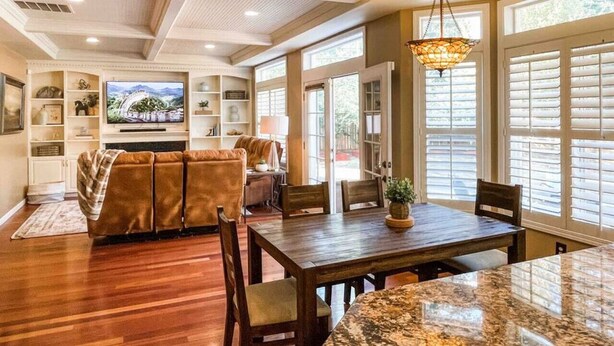A spacious living room with a large sectional sofa, a dining area with a wooden table, and a television mounted on the wall. - Tacoma Retreat-  Fireplace & AC! (Lakewood)