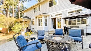 A patio area with a fire pit, outdoor seating, and a covered grill area. - Tacoma Retreat-  Fireplace & AC! (Lakewood)