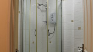 Cabina doccia in vetro con soffione a mano e pannello comandi a parete.