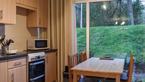 Una cucina con mobili in legno, un forno a microonde, un fornello e un tavolo da pranzo con sedie.