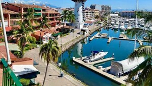 A marina with boats docked, a lighthouse, and buildings in the background. - CONDO PSOL BY TRVL2HM (Puerto Vallarta)