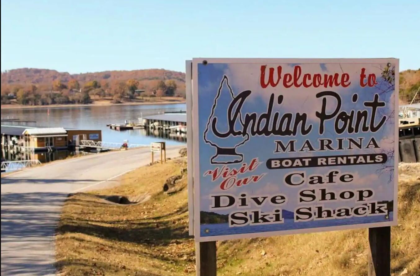 Cartell de benvinguda als visitants a Indian Point Marina, destacant serveis com lloguer de vaixells, un cafè, botiga de submarinisme i un refugi d'esquí.
