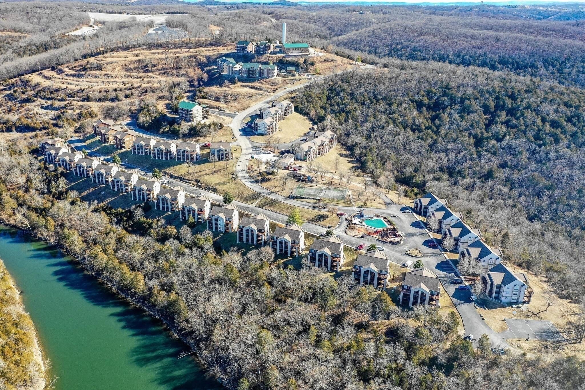 Une vue aérienne d’un quartier résidentiel avec plusieurs maisons, une piscine et une rivière.