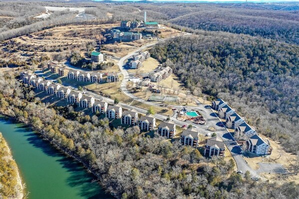 Vista aérea de una zona residencial con varias casas, una piscina y un río.