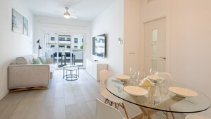 A modern living room with a glass dining table, white sofas, and a view to the outside. - Ref. 377638 (Motril)