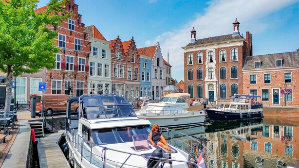 En kanal med både, en overdækket terrasse og bygninger med røde og hvide facader.