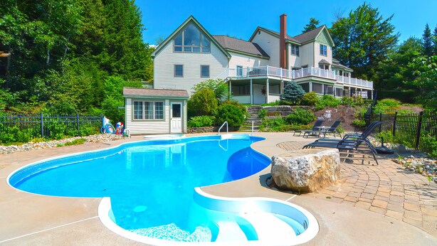 A swimming pool with a curved design, surrounded by a paved deck. - 9 Bedroom Estate, Sleeps 24, Pool, Hot Tub, Movie Theater, Game Room (Newry)
