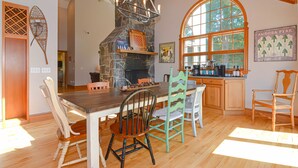 A kitchen with a stone fireplace, wooden dining table, and chairs. - 9 Bedroom Estate, Sleeps 24, Pool, Hot Tub, Movie Theater, Game Room (Newry)