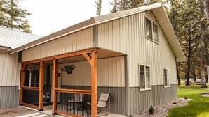 A single-story building with a covered porch, a small garden area, and a gravel driveway. - Convenient Mountain Comfort (Lincoln)