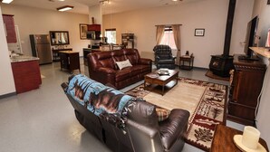 A living room with a sofa, a coffee table, a fireplace, and a kitchen area in the background. - Convenient Mountain Comfort (Lincoln)