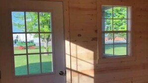 A wooden room with a door and two windows. - Valley Cabin (Spring Valley)
