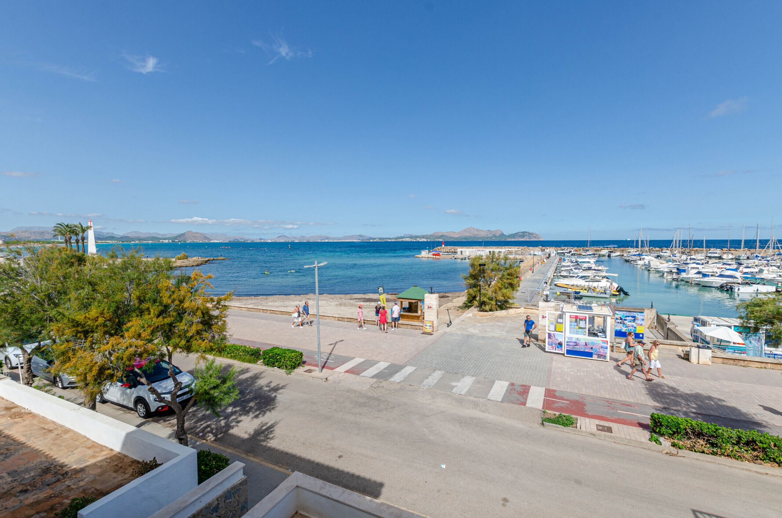 Un puerto deportivo con barcos, un faro y una pasarela para peatones.