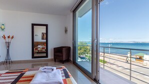 A hotel room with a large window, a bed with a quilt, a chair, and a mirror. - YourHouse Mulet, cozy sea-view apartment (Can Picafort)