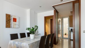 A dining area with a table, chairs, a potted plant, and a painting on the wall. - YourHouse Mulet, cozy sea-view apartment (Can Picafort)