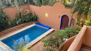 A swimming pool with a blue border, surrounded by a garden with various plants and a decorative wall. - Casa Fiesta, Best Place to Rest, 1 Block Away From the Beach Owner Managed (Rincón de Guayabitos)