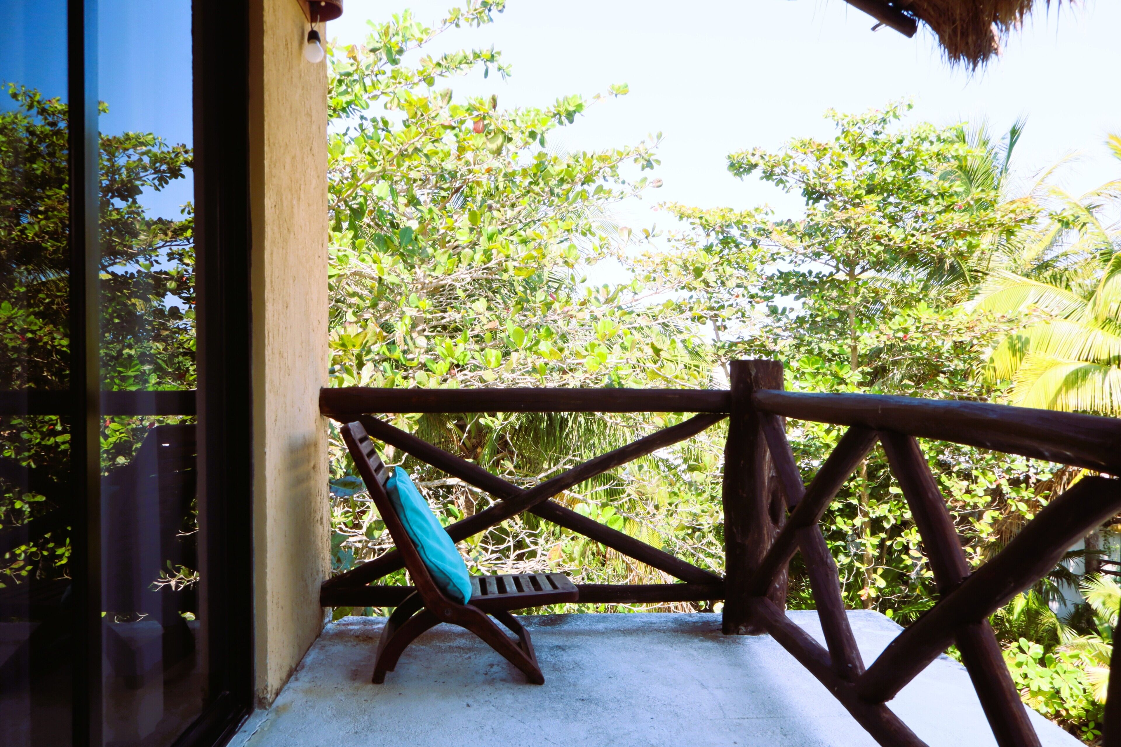 Un balcon doté d’une balustrade en bois, d’un banc et offrant une vue sur une végétation luxuriante.