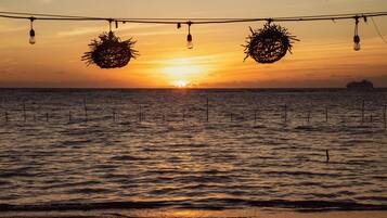 A sunset over a calm sea with decorative lights and a ship in the distance.