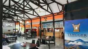 A spacious restaurant with high ceilings, exposed beams, and a variety of seating arrangements including tables and chairs. - Tengger Guest House (Pasuruan)