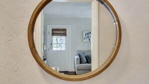 A round mirror with a wooden frame on a textured wall.