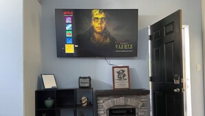 Un salon avec une cheminée, un téléviseur fixé au mur et une porte.