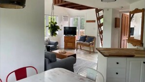 Amplia sala de estar con una mesa de comedor, un sofá, un televisor y un mueble de madera.
