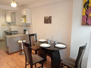 Cozy apartment with a kitchenette and dining area, featuring a round table and modern appliances.
