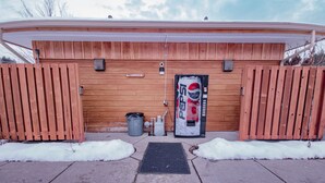A wooden building with a closed gate, a Pepsi vending machine, and a trash can. - Main floor studio well-furnished room.  Unit 2 with bath/shower bidet toilet (Pinehurst)