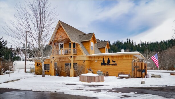 A large wooden building with a balcony, a flag, and a sign that reads "BY THE WAY SUTTONS". - Main floor studio well-furnished room.  Unit 2 with bath/shower bidet toilet (Pinehurst)