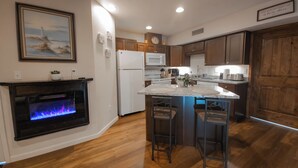 A modern kitchen with wooden cabinets, a central island, a built-in oven, and a decorative fireplace. - Main floor studio well-furnished room.  Unit 2 with bath/shower bidet toilet (Pinehurst)