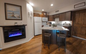 Enjoy cooking in this kitchen with a central island, bar stools, microwave, and stainless steel refrigerator.