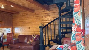 A wooden interior with a brown leather sofa, a patterned throw, a staircase, and a wooden ceiling. - Cabin 1 on the Kenai River!best view cabin (Sterling)