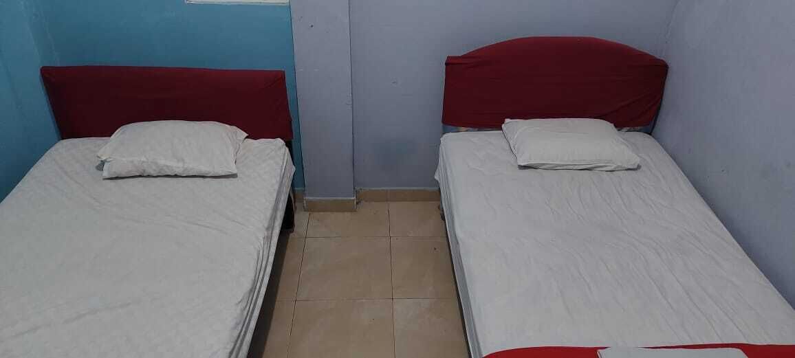 A room with two single beds, each with a red headboard and white bedding.