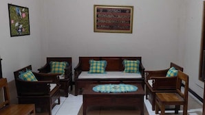Een woonkamer met een zithoek, twee fauteuils, een salontafel en een decoratief object aan de muur.