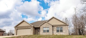 A two-story house with a garage, brick exterior, and a clear sky.