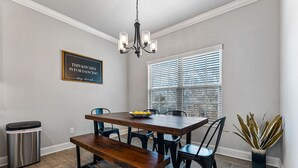 A dining area with a wooden table, black chairs, a bench, a trash can, and a potted plant. - Back 40 Bike-In/Out, 3 Miles to Bike Park (Bella Vista)