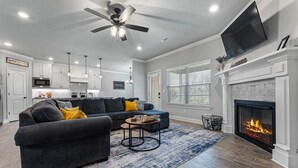 A modern living room with a dark grey sectional sofa, a round coffee table, and a fireplace. - Back 40 Bike-In/Out, 3 Miles to Bike Park (Bella Vista)