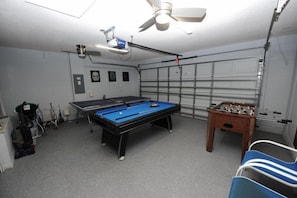 Une pièce équipée d’une table de billard, d’un baby-foot et d’un ventilateur de plafond.