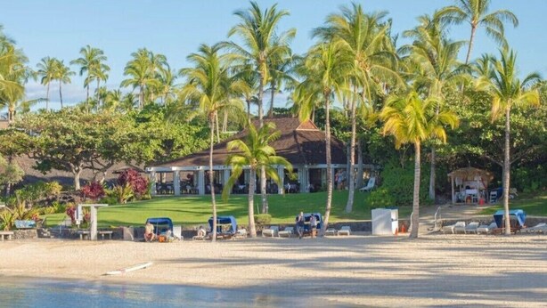 Un resort con piscina, palmeras y un edificio de techo inclinado.