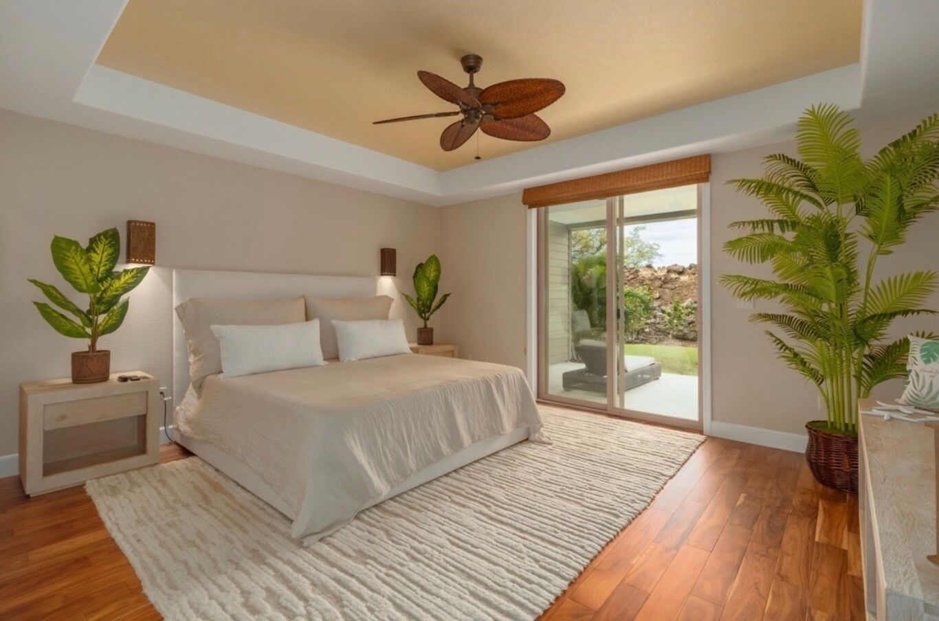 Un dormitorio con cama, ventilador de techo, ventana grande y vistas al exterior.