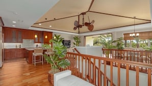 Un espacio habitable amplio con piso de madera, un sofá blanco y un balcón con barandilla.