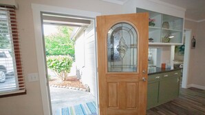 Eine Holztür mit Glasfenster, ein grüner Schrank und ein kleiner Garten, der durch die Tür zu sehen ist.