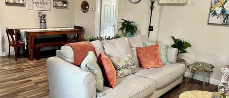 A living room with a sofa, coffee table, and a dining area with a table and chairs.